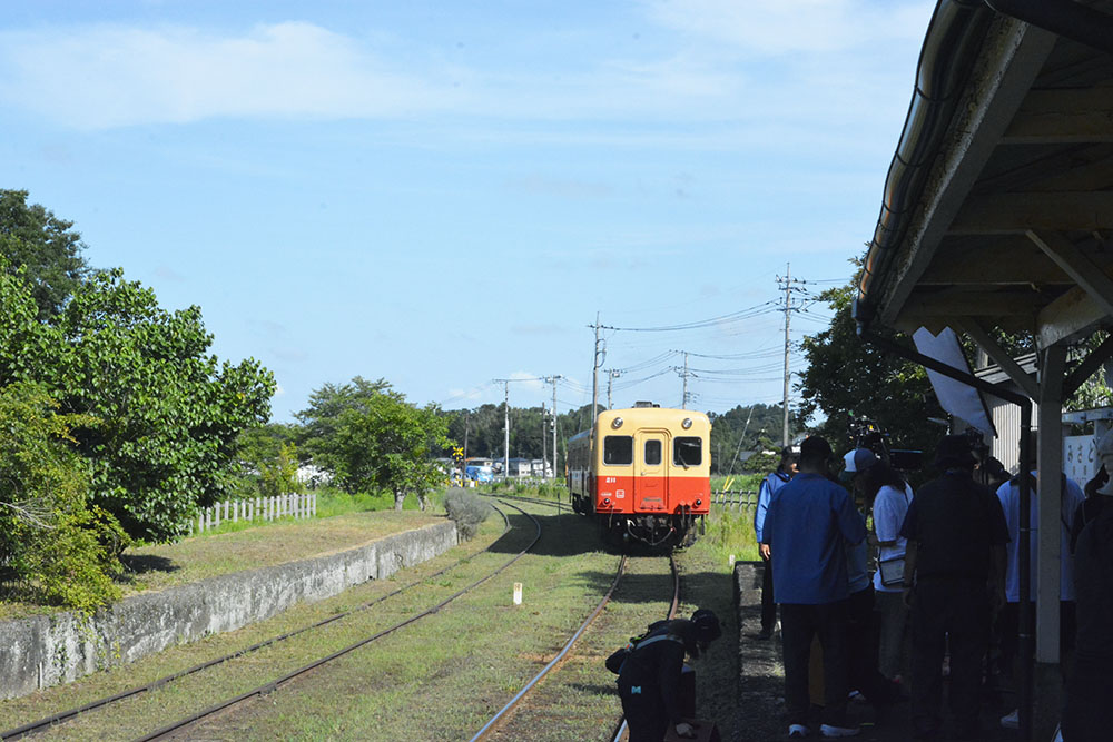 ミキプルーンのCM撮影で本物の電車を待つ